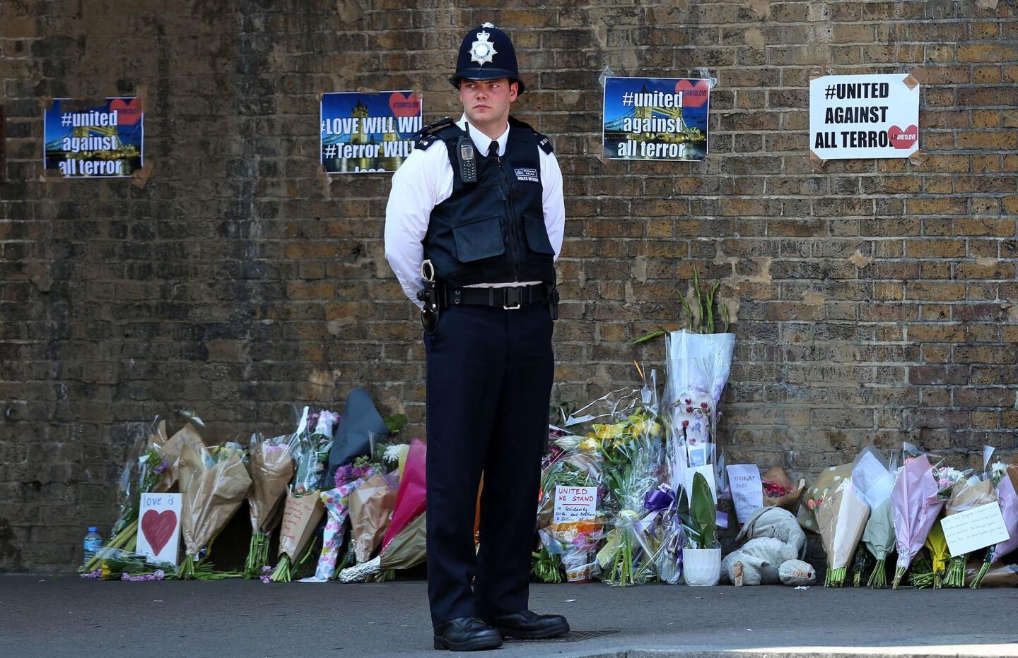 A police officer stands on duty near tributes and flowers at a police cordon in the Finsbury Park area of north London following a vehicle attack on pedestrians. One person died and 10 people were injured when a van drove into a crowd of Muslim worshippers near a mosque in London in the early hours of Monday.