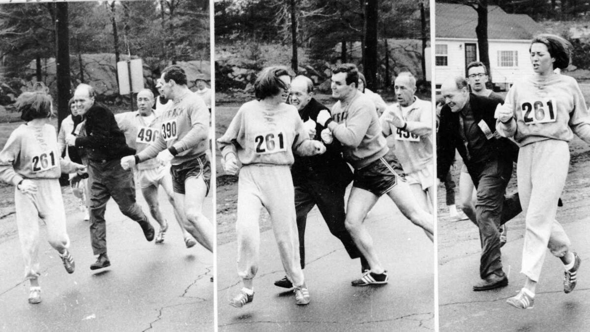Boston Marathon official Jock Semple tries to eject Kathrine Switzer (261) in 1967, but Tom Miller runs interference and blocks him out. (Harry Trask / Associated Press)