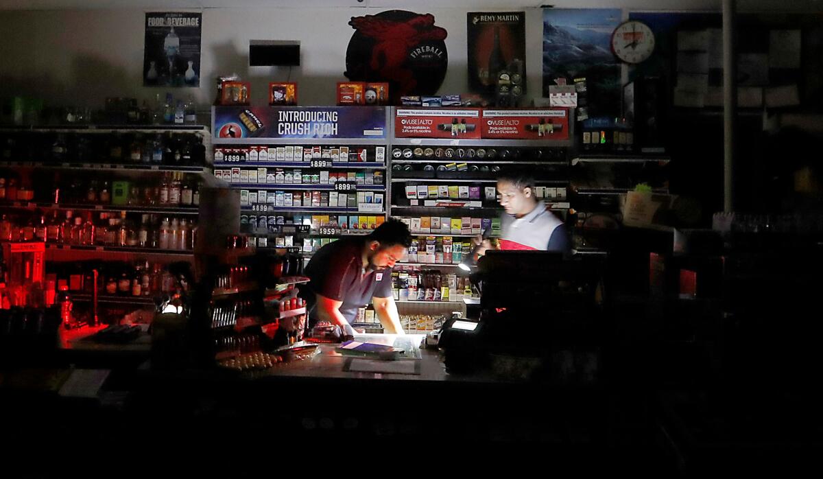 Shopkeepers Sodhi Singh, left, and Navneet Singh prepare to close down their gas station and convenience store in Healdsburg in Sonoma County after the lights went out ahead of an expected high-wind event in the area of the Kincade fire.