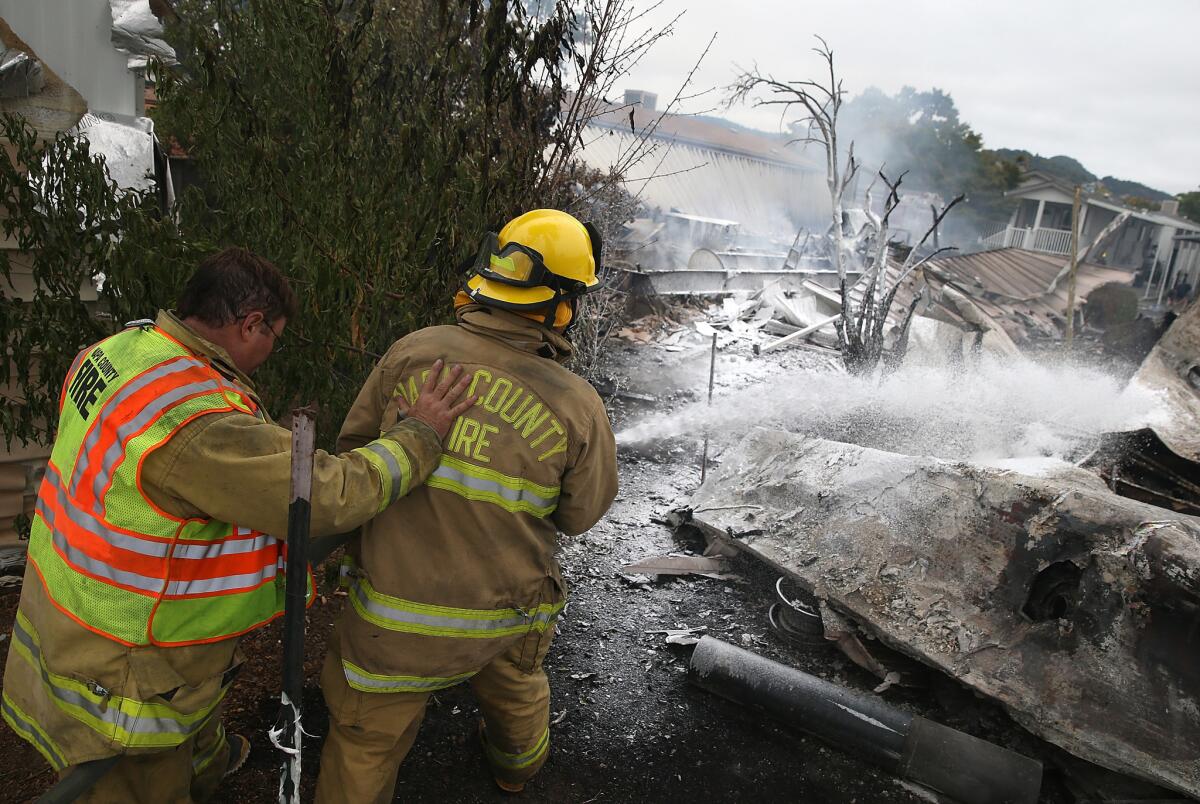Napa County firefighters spray foam on hotspots from a fire at a mobile home park following the reported 6.0 earthquake in Napa.