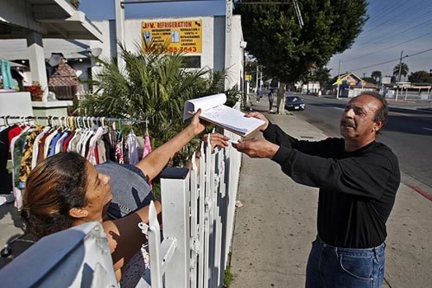 Eddie Caire, a civic activist and former labor organizer from the Florence-Firestone neighborhood just north of Watts, collects a signature from Beda Padilla in favor of bringing a Wal-Mart to the area.