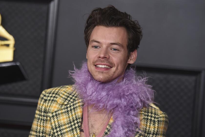 A man smiling in a yellow plaid jacket and purple boa