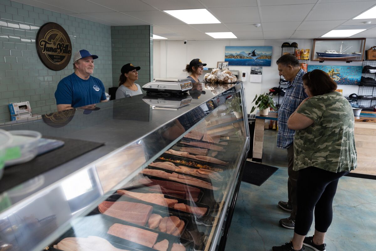 Employees behind the cases at TunaVille Market and Grocery help customers shopping for fish.