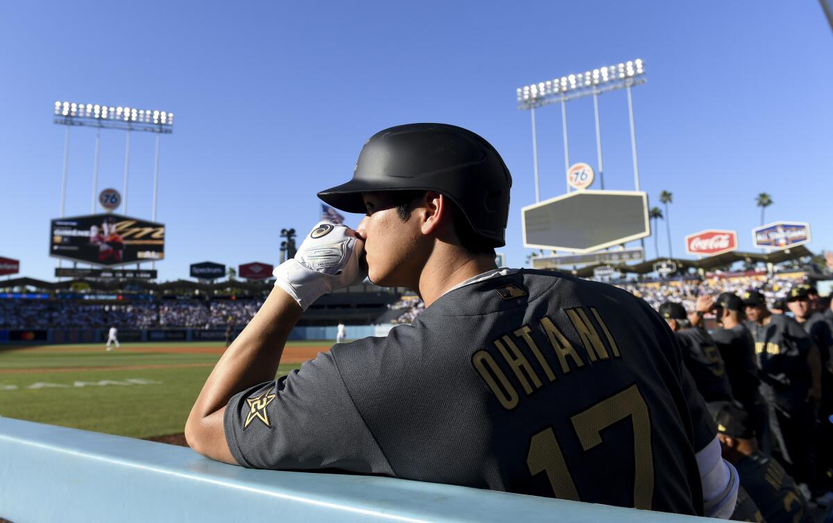 A man rests his chin on his fist in the dugout of a baseball field.