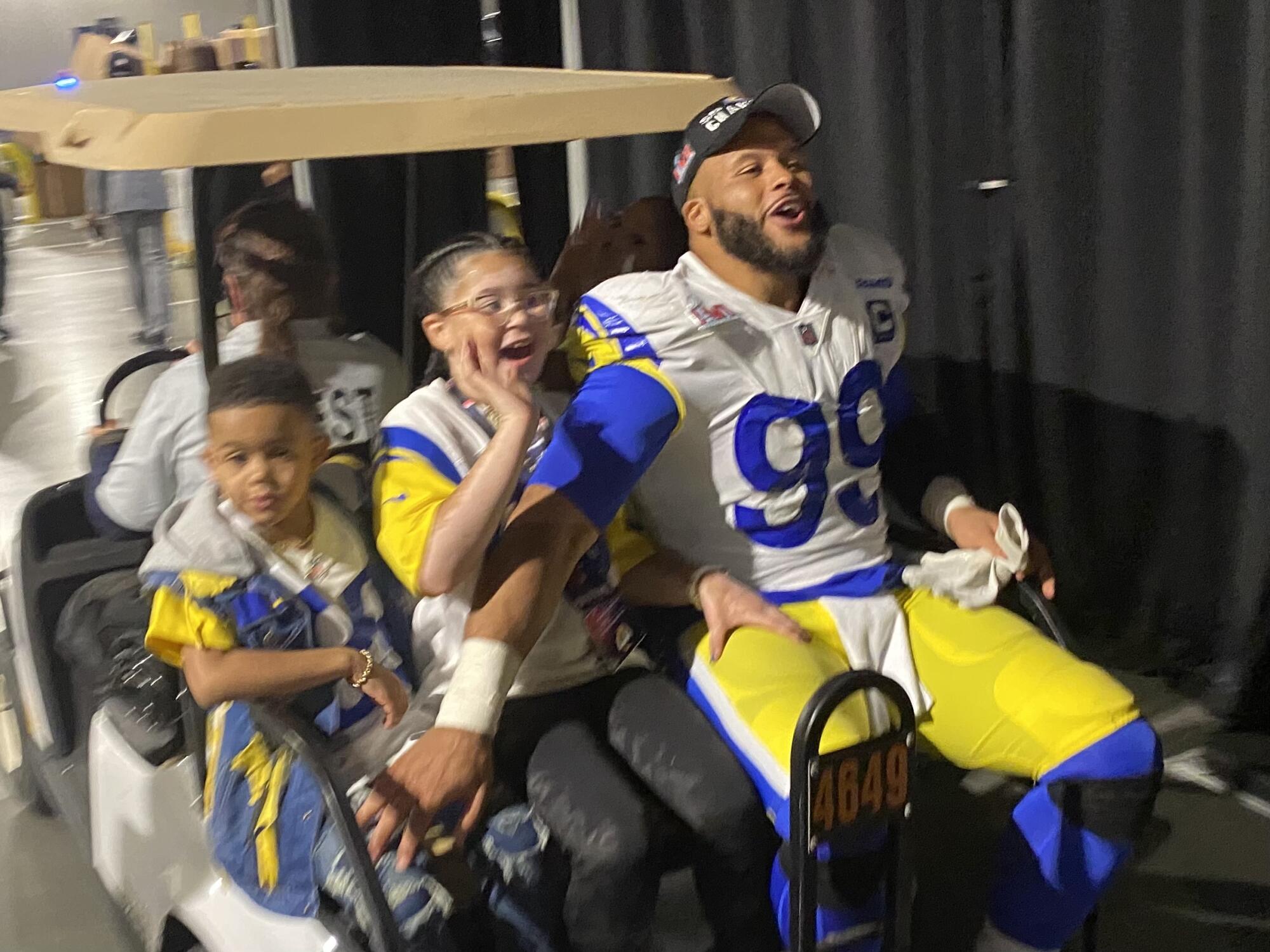 Aaron Donald celebrates with his children while riding on the back of a golf cart at SoFi Stadium.