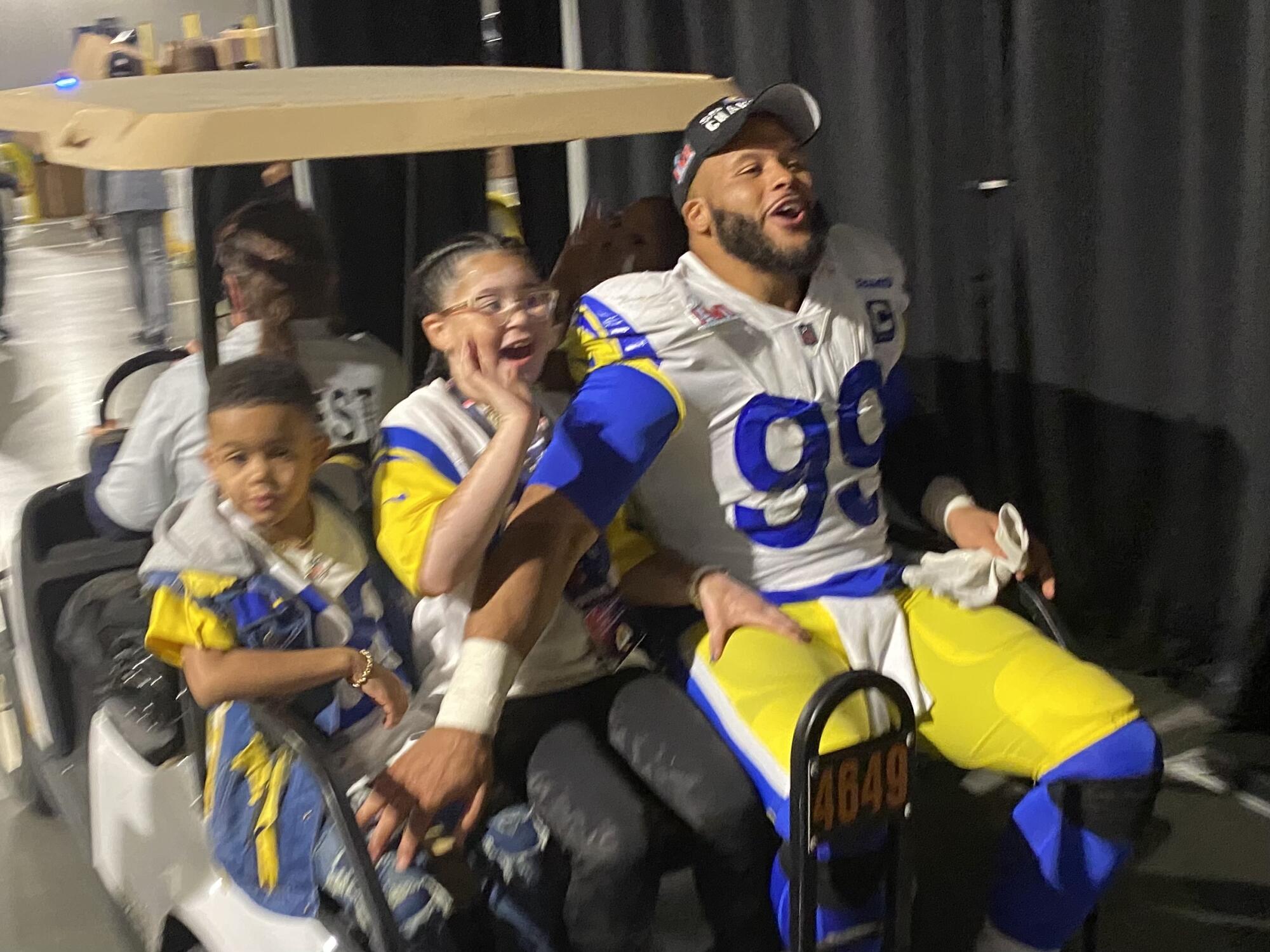 Aaron Donald, SoFi Stadyumu'nda golf arabasının arkasında çocuklarıyla birlikte kutlama yapıyor.