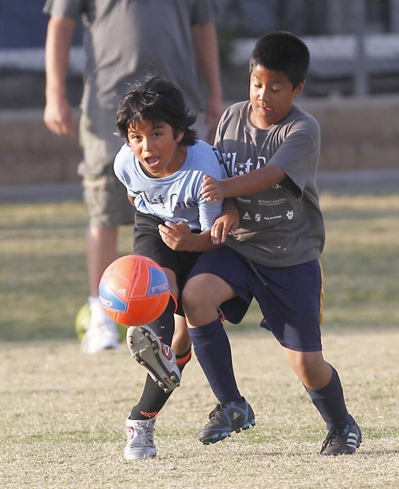 Sonora's Ken Figueroa, left, boots the ball upfield as Pedro Martinez bumps into him during a boys' 3-4 silver division game Friday.