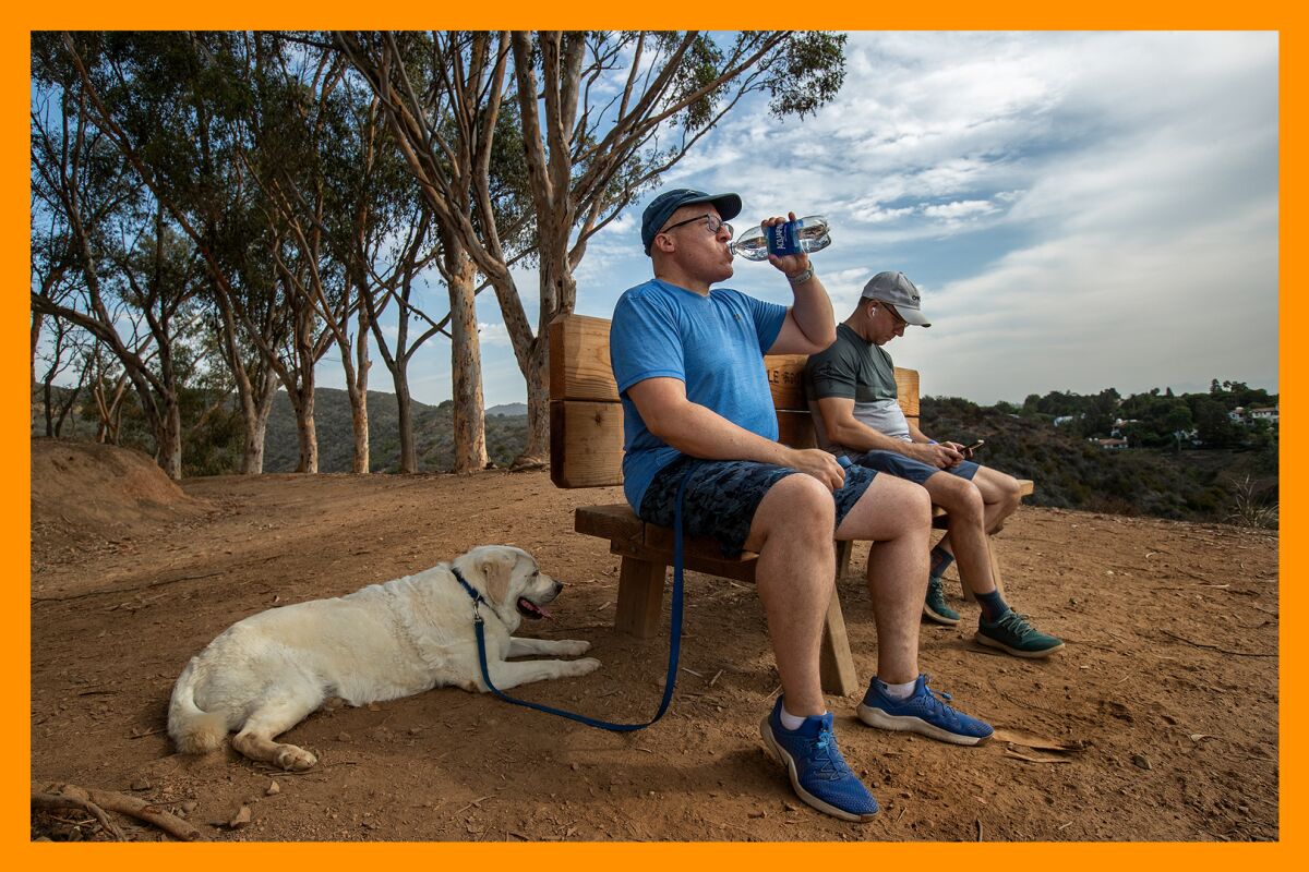 Two men and a dog take a break while walking the Inspiration Point Loop Trail.