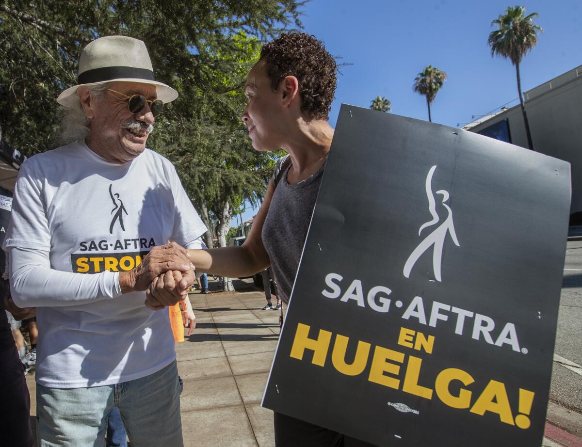 Actor Edward James Olmos greets director Zetna Fuente, while joining the Writers Guild/SAG-AFTRA picket line.