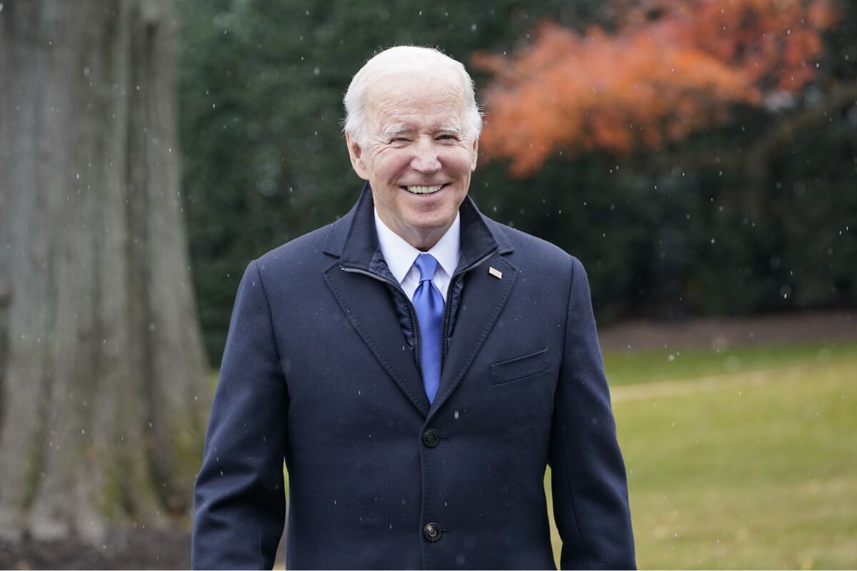 President Biden smiles and wears a jacket outside the White House