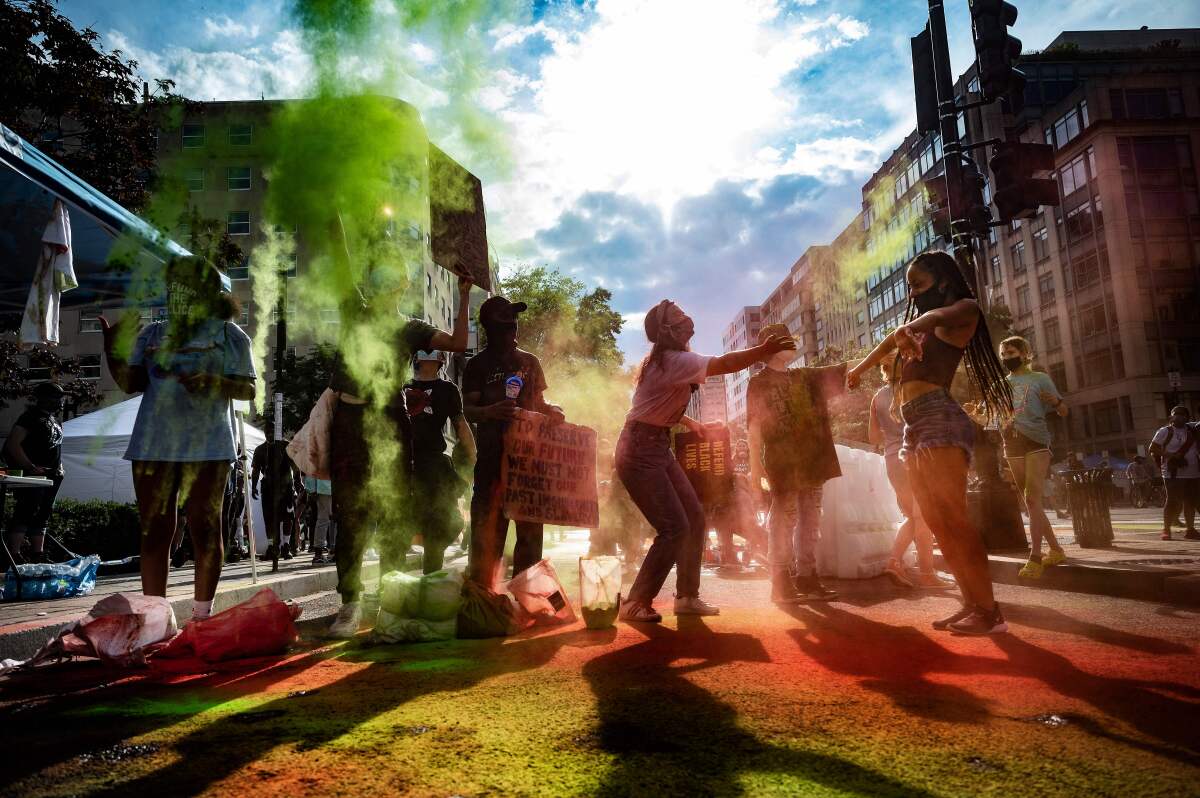 People gather for a march as colorful powder falls on the crowd