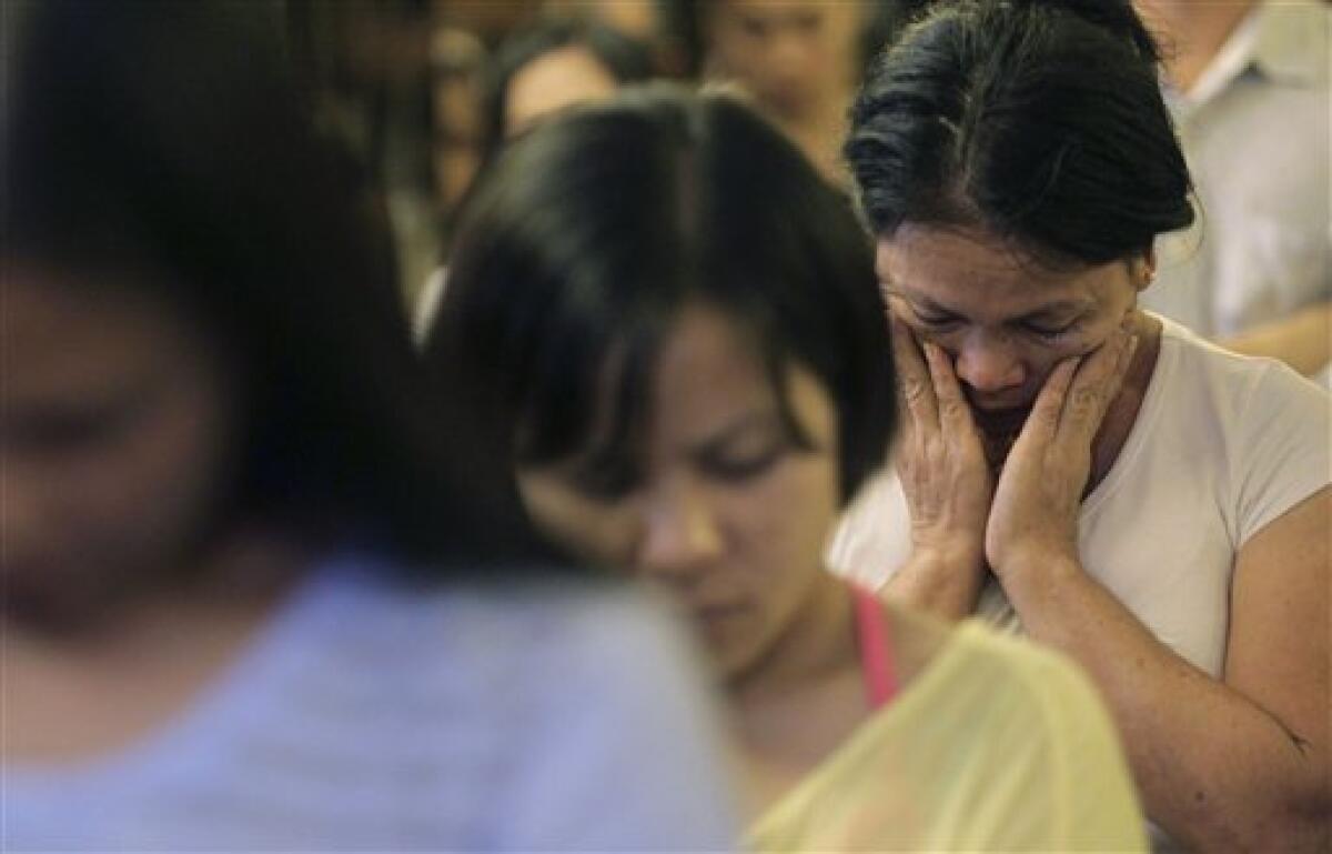 Filipino women pray during a mass for the Hong Kong victims who was killed in Monday's hostage standoff in the Philippines in Hong Kong Wednesday, Aug. 25, 2010. A charter flight brought the bodies of eight victims of a bus hijacking in the Philippines back home to Hong Kong on Wednesday. Hong Kong has been shaken by the bloody conclusion to Monday's hostage standoff in the Philippine capital in which an ex-policeman held a busload of Hong Kong tourists at gunpoint in a bid to win his job back before opening fire on the captives. (AP Photo)