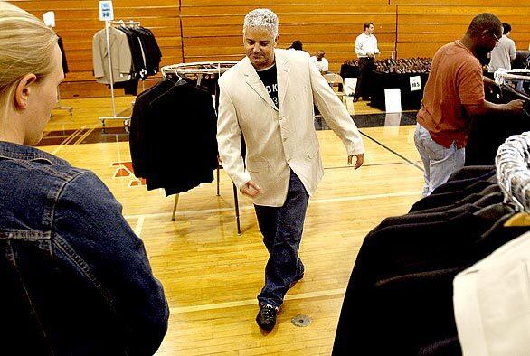 Sporting a new jacket, Anis Kouhen, 45, of Los Angeles dances around the gym floor as he tries on suits with Working Wardrobes volunteers at Los Amigos High School in Fountain Valley. Working Wardrobes' Men's Day of Self-Esteem offers job-market training for men who have experienced homelessness, alcohol or substance abuse, or other traumas.