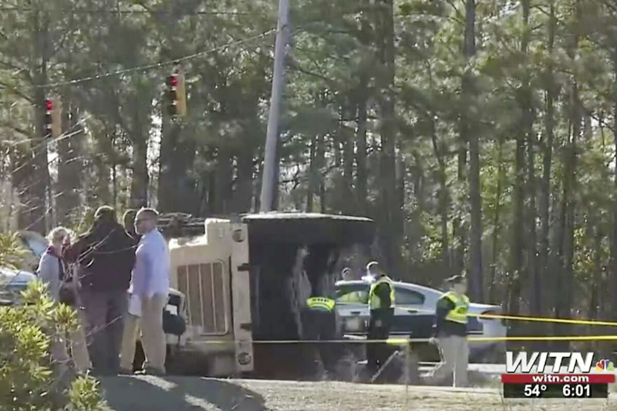 In this image taken from video, authorities work at the scene of a fatal crash after a military truck overturned, Wednesday, Jan. 19, 2022, near Camp Lejeune, N.C. Two U.S. Marines were killed and 17 others were injured when the truck they were riding in overturned Wednesday and ejected them near their base in North Carolina, authorities said. (WITN via AP)
