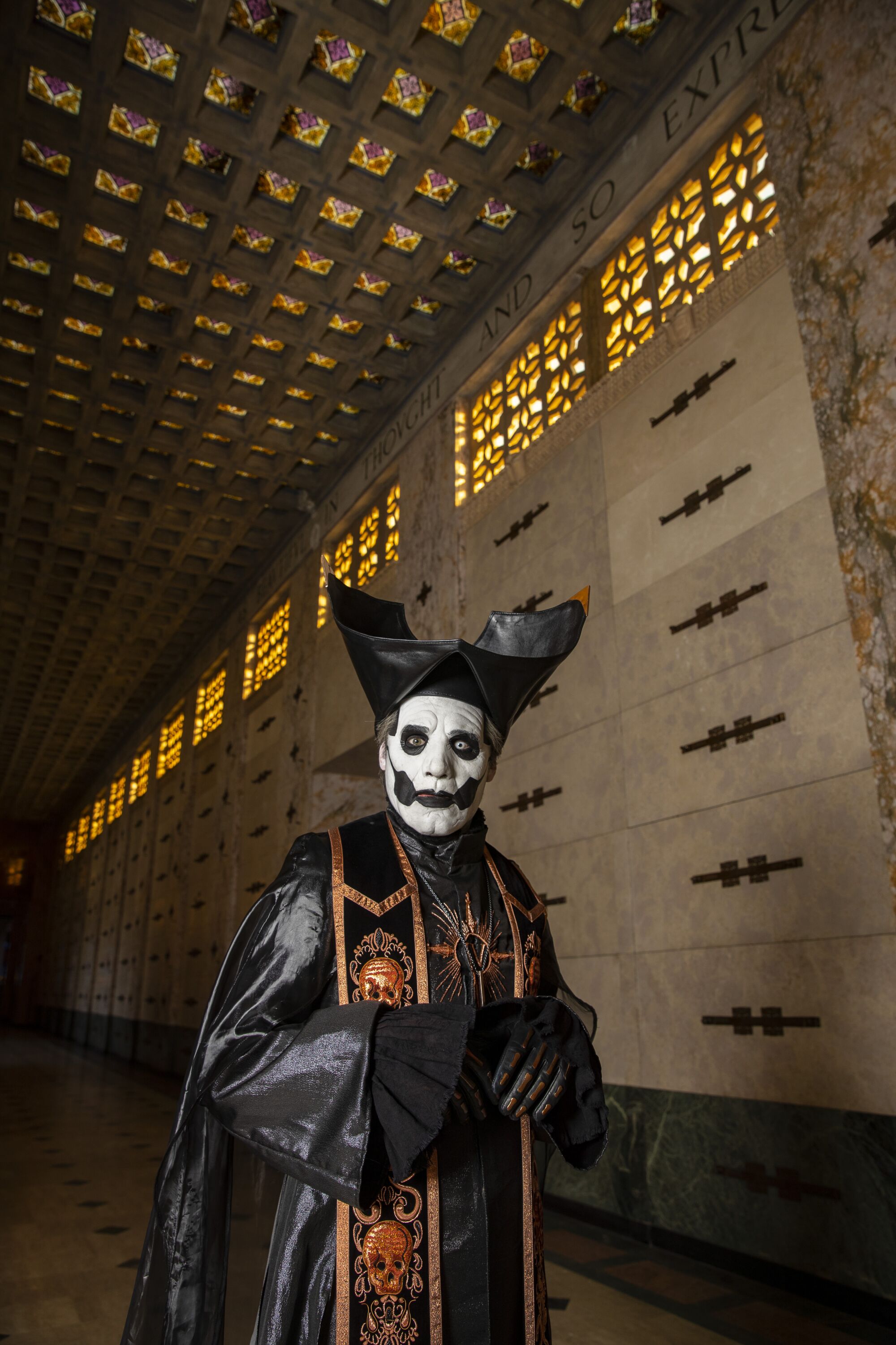 A man in white face paint and pope-like costume