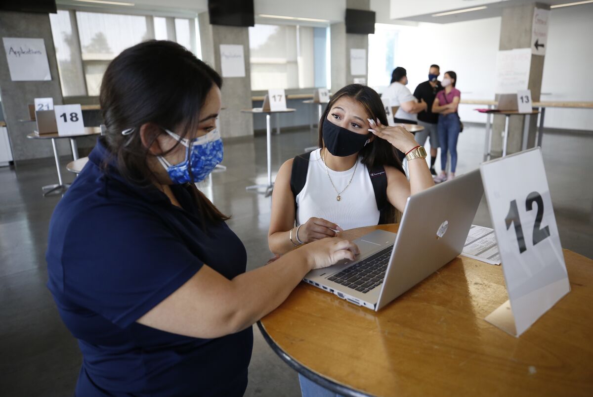 Two women stand at a counter looking at a laptop computer