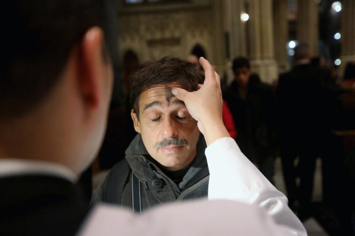 A man receives a cross of black ashes on his forehead on Ash Wednesday at St. Patrick's Cathedral in New York.