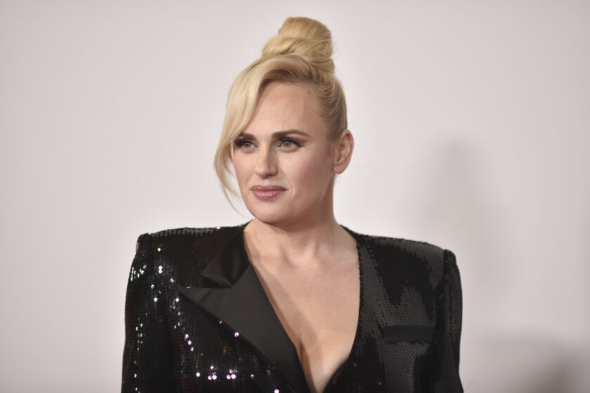 A woman with a bun of blond hair wearing a sparkly black blazer