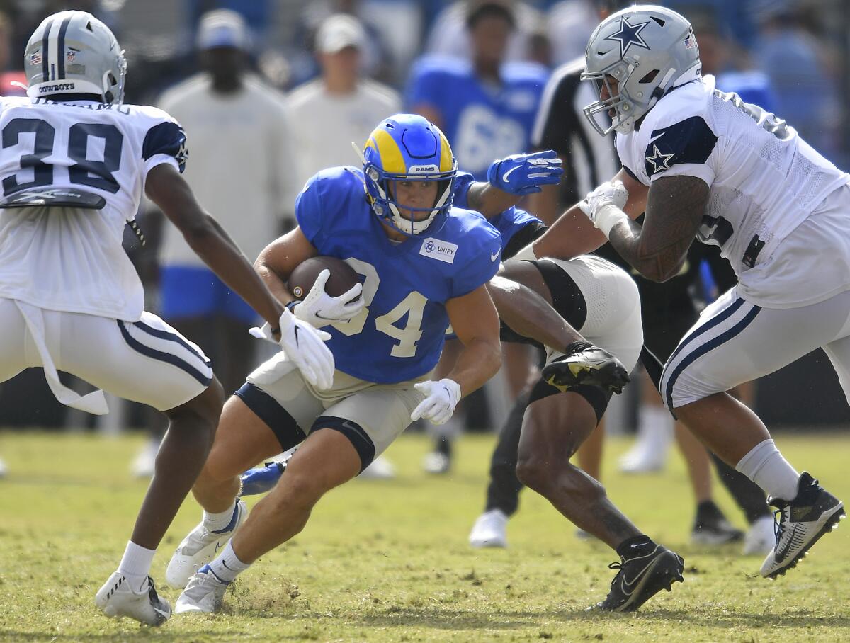 Los Angeles Rams running back Jake Funk runs between Dallas Cowboys' Israel Mukuamu, left, and Austin Faoliu during NFL football practice Saturday, Aug 7, 2021, in Oxnard, Calif. (AP Photo/John McCoy)