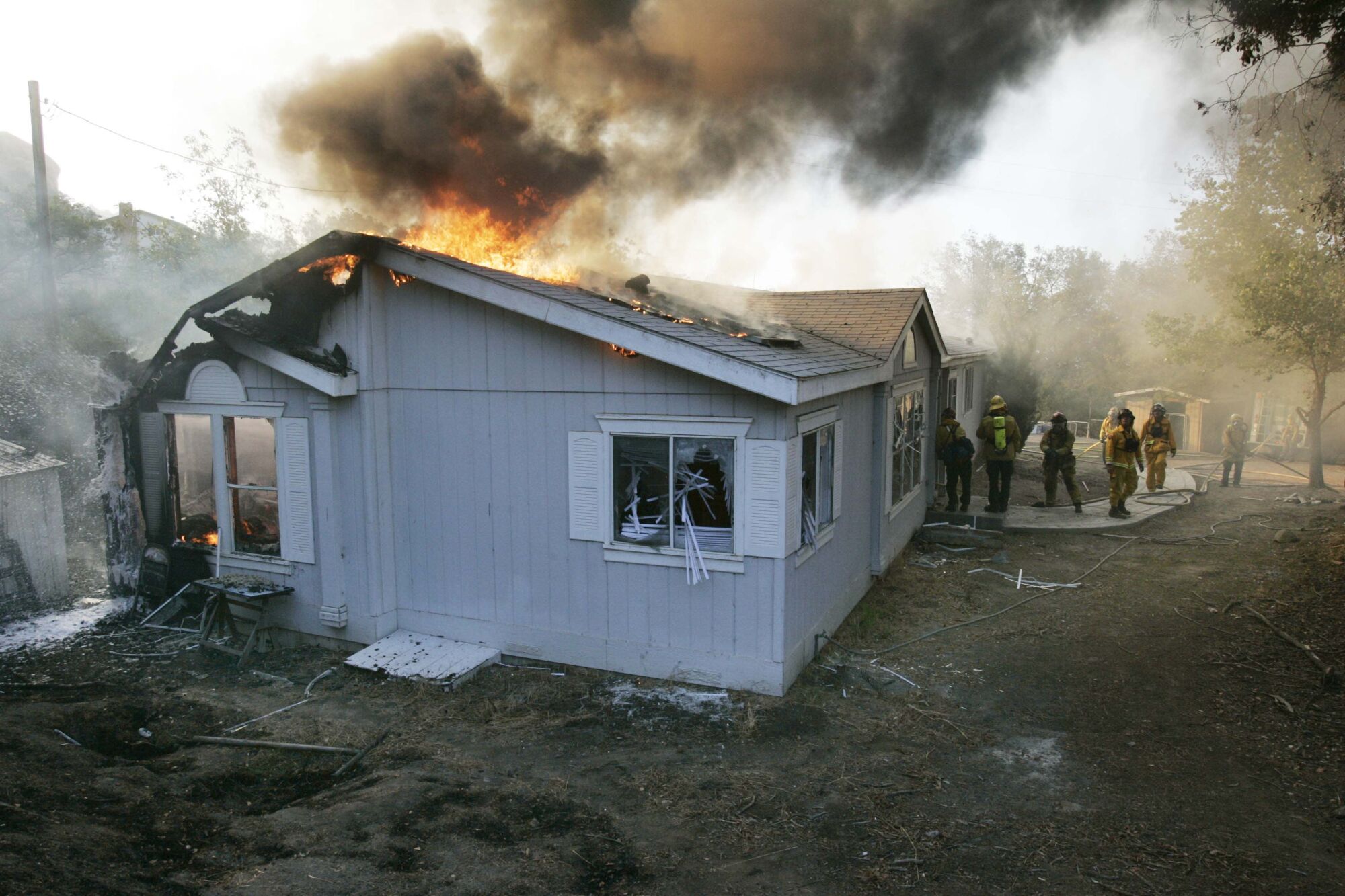 Firefighters battle a house fire on Honey Springs Road, north of Dulzura, during the Harris fire in 2007.