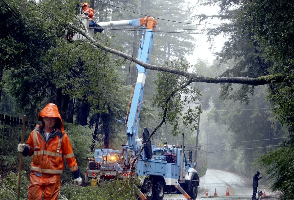 FILE - Pacific Gas & Electric crews work to clear a downed tree over Highway 9 north of Boulder Creek, Calif., on Jan. 8, 2017. A major storm is headed toward Northern California this weekend, promising to drop heavy snow in the Sierra Nevada and rain throughout the region. Forecasters say the storm is on track to hit coastal areas north of San Francisco, on the night of Saturday, Dec. 11, 2021, and bring light rain. PG&E is sending crews to clear vegetation away from power lines to reduce the chance of power outages. (Kevin Johnson/The Santa Cruz Sentinel via AP, File)