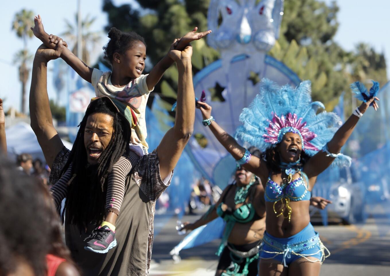 Jerome Garbutt gives his daughter Jahzara, 5, a ride on his shoulders while marching with members of Trinifeters, a Caribbean dance group, as they perform during the 29th Annual Martin Luther King Jr. Kingdom Day Parade.