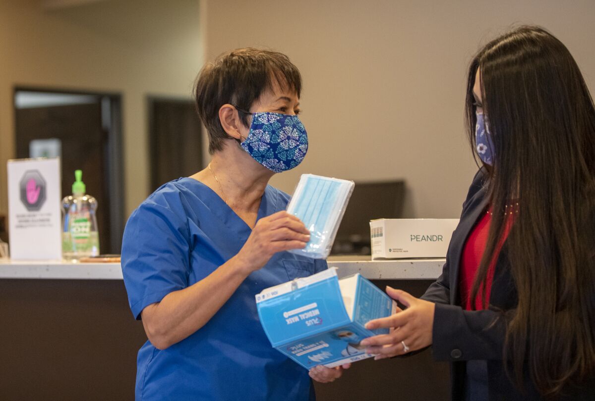  Dr. Quynh Kieu, left, founder and president of Project Vietnam Foundation, receives masks from Vivian Cao.