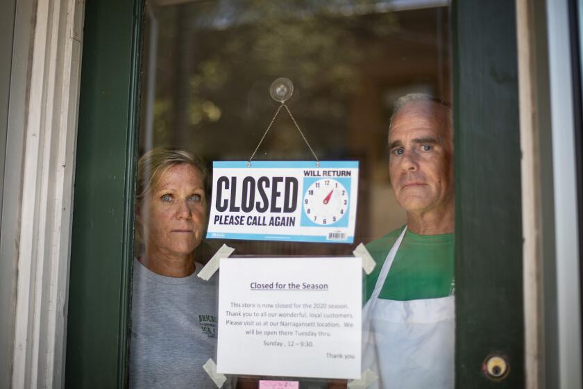 Steve, right, and Chris Brophy, husband and wife owners of Brickley's Ice Cream, look out from the store they closed after teenage workers were harassed by customers who refused to wear a mask or socially distance, in Wakefield, R.I., Wednesday, July 29, 2020. "Some of them don't believe it's real (COVID-19) and some don't think it's a big deal, I do," Steve Brophy said, adding that he would rather close than put young workers and customers at risk of harassment, and the virus. "It's like it's OK to be a jerk in this environment." (AP Photo/David Goldman)