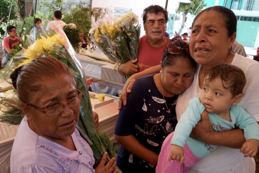 Facunda VIllanueva PÃ©rez 67, whose sister is among the 11 dead in the town of Atzala, holds her grandchild and mourns with relatives at the victims wake on Wednesday.