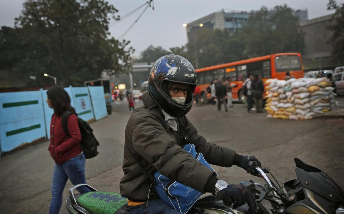 An Indian man riding his motorcycle covers his face from smog in New Delhi. During his visit this week to the Indian capital, President Obama will breath some of the world's dirtiest air.