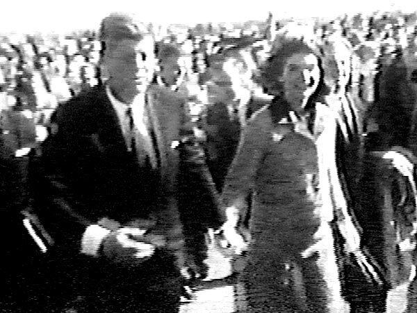 President Kennedy and his wife hold hands before getting in their convertible limousine at Love Field for the motorcade through Dallas. Her suit was a Chanel knockoff created by a New York dress shop so she could indulge her French tastes and still buy American.