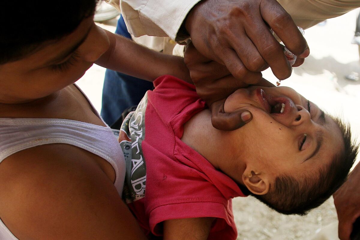 A health worker administers a polio vaccination to a child in Karachi, Pakistan, on Sept. 19.
