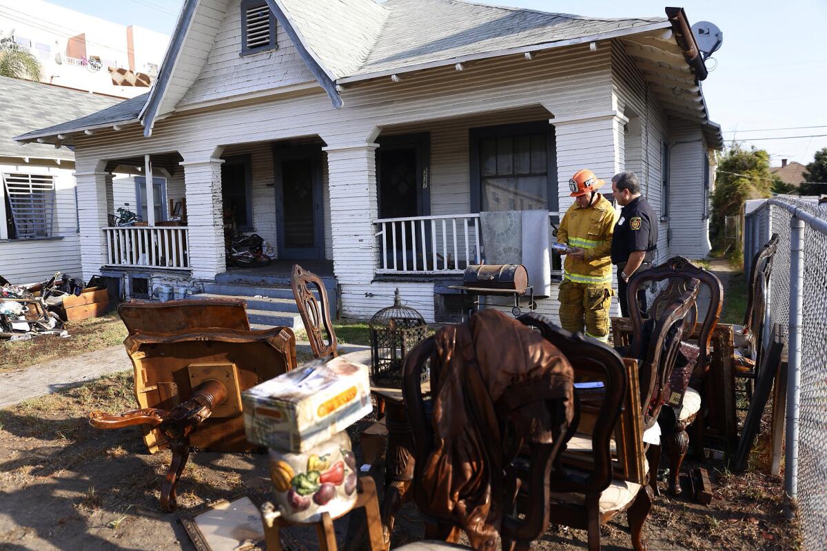 LAFD Capt. Jaime Moore, left, and LAFD Inspector John Novela walk around a burned home in the 200 block of West 50th Street in Los Angeles' South Park neighborhood.