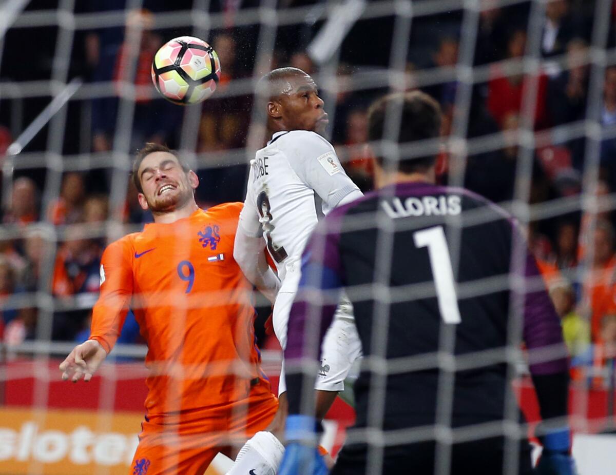 Netherlands' Vincent Janssen, left, heads the ball with France's Djibril Sidibe, center, while France's goalkeeper Hugo Lloris looks on during the World Cup Group A qualifying soccer match in the ArenA stadium in Amsterdam, Netherlands, Monday, Oct. 10, 2016. France defeated Netherlands 1-0. (AP Photo/Peter Dejong)
