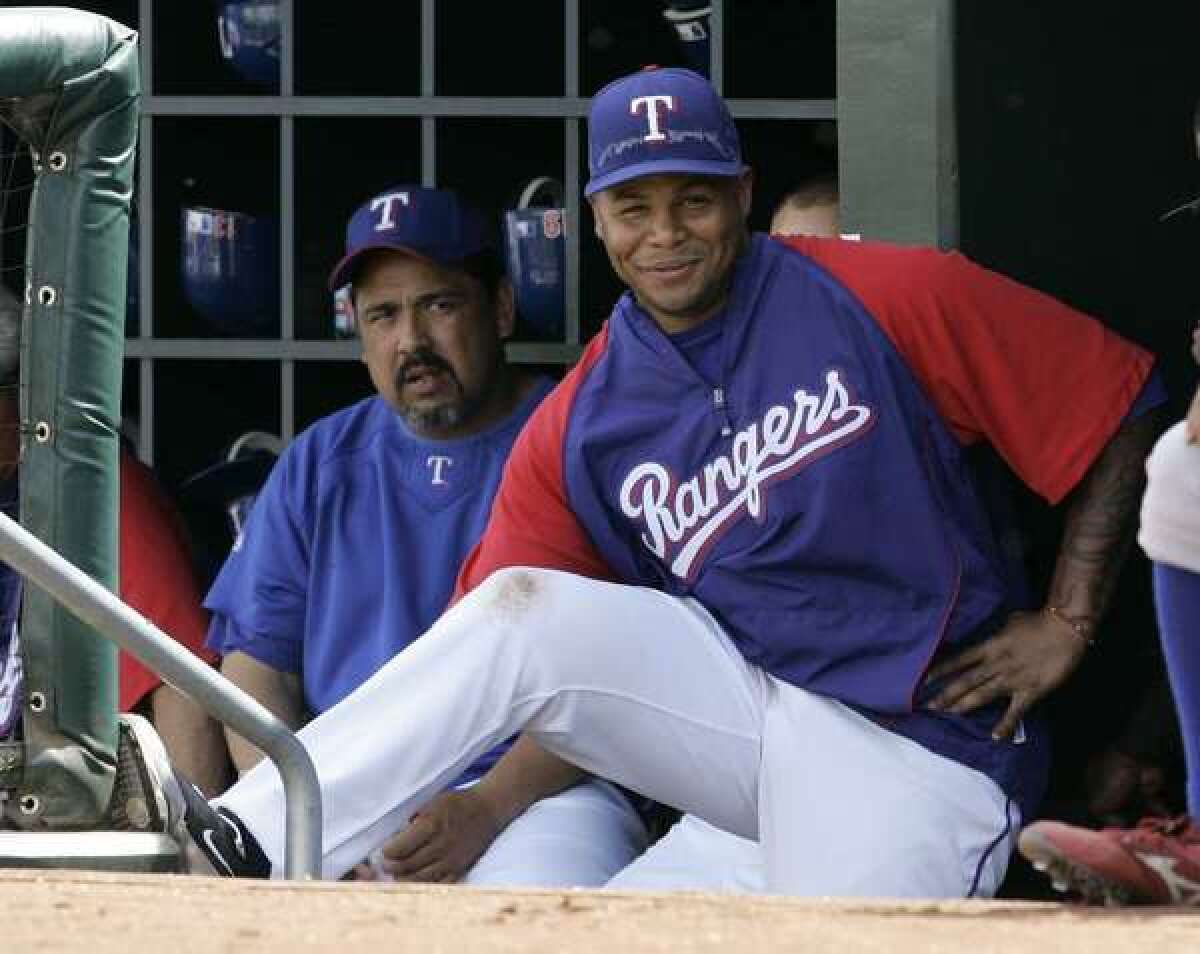 Texas Rangers' Andruw Jones, center, and Eddie Guardado, left, watch a spring training baseball game against the Oakland Athletics.