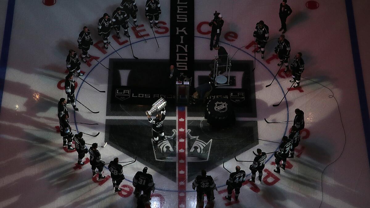 Kings captain Dustin Brown lifts the Stanley Cup at center ice during the team's championship banner-raising ceremony Wednesday.