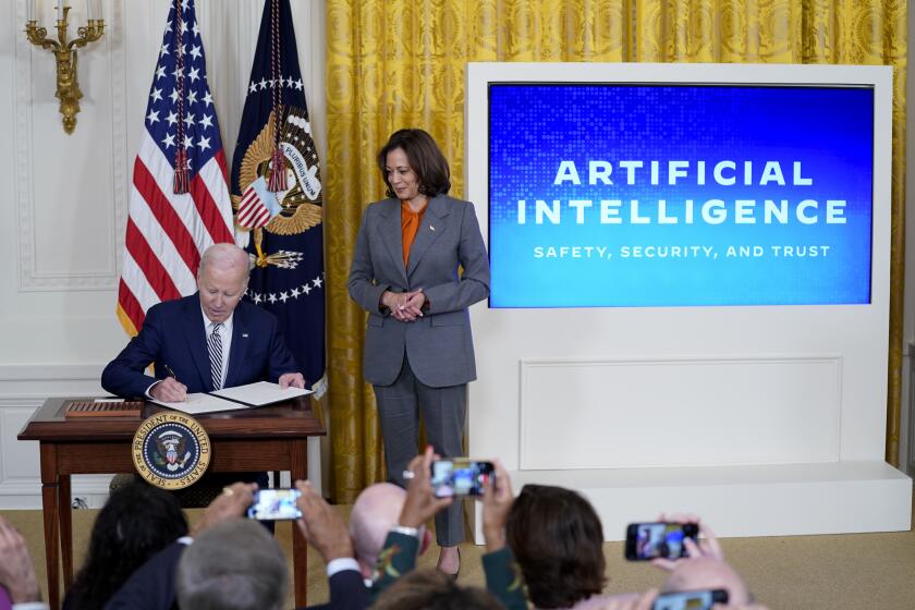 President Joe Biden signs an executive on artificial intelligence in the East Room of the White House, Monday, Oct. 30, 2023, in Washington. Vice President Kamala Harris looks on at right. (AP Photo/Evan Vucci)