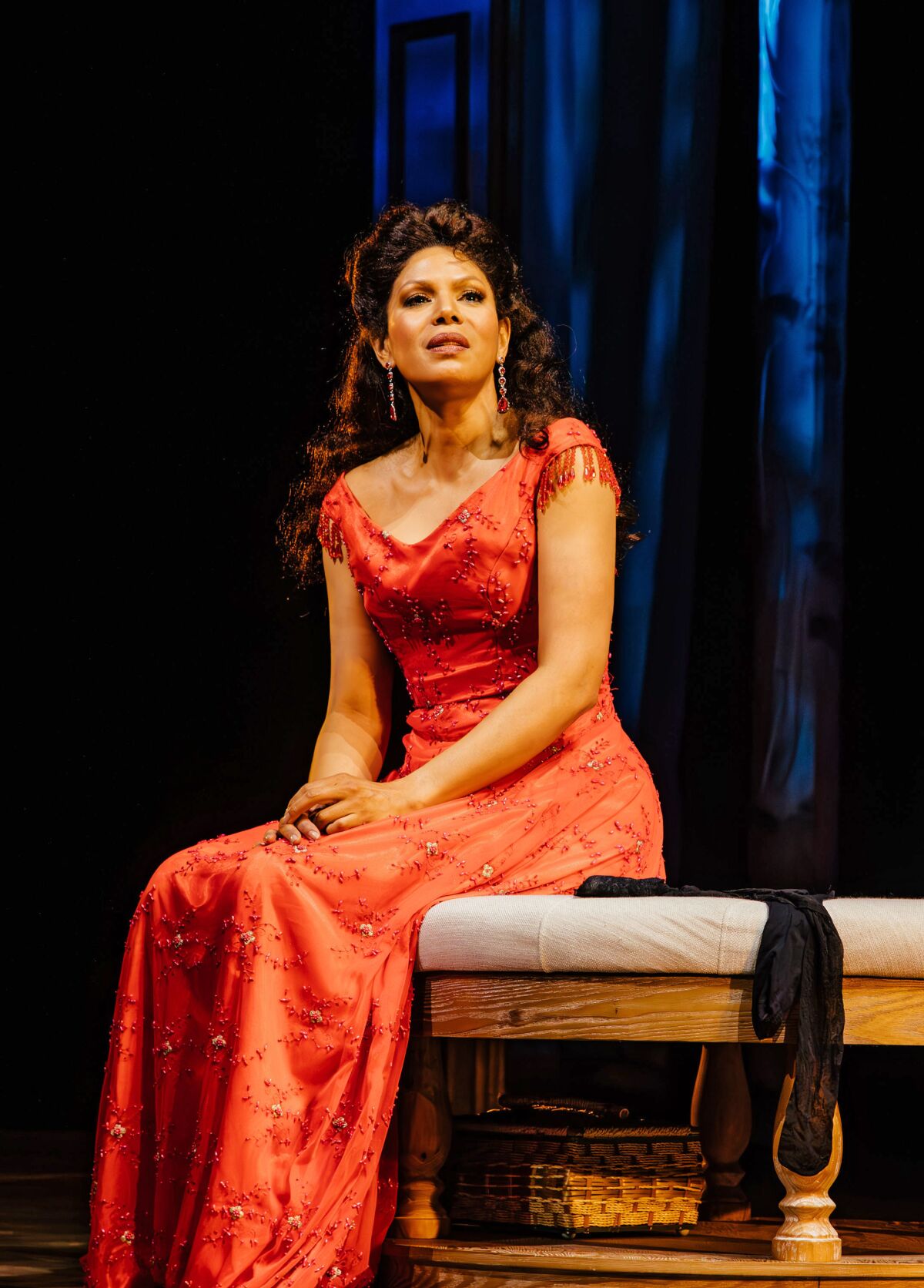 Merle Dandridge wears a red gown while sitting on a bench in "A Little Night Music."