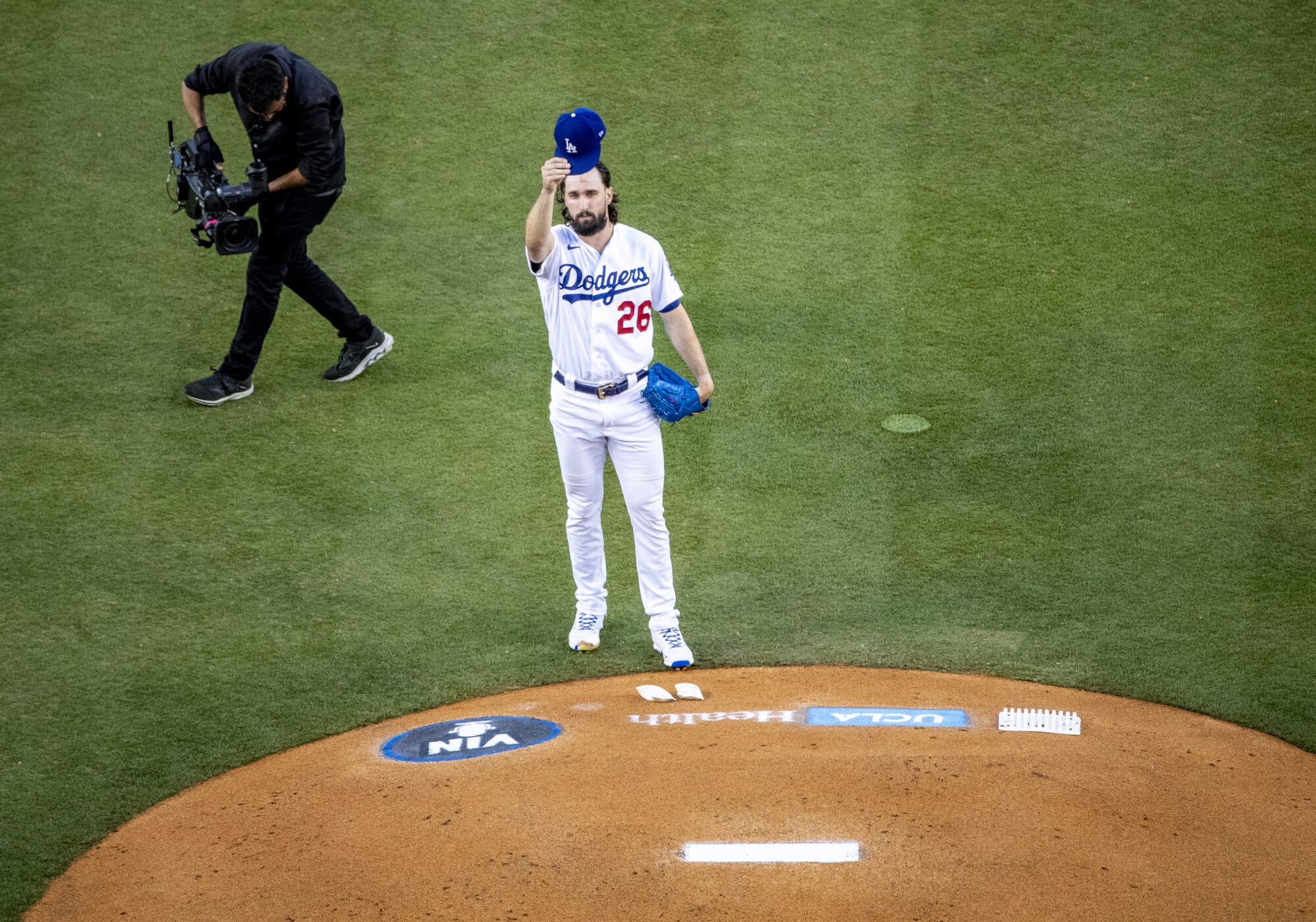 Dodgers starting pitcher Tony Gonsolin raises his cap in front of the press box in honor of Vin Scully.