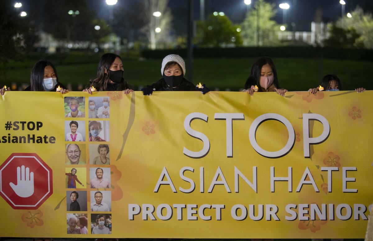 A group of Asian American community and faith leaders hold a banner.