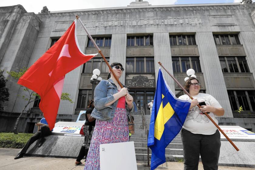 Engaged couple Karen Welch, left, and Brittany Raymond, both of Brandon, Miss., wave equality flags outside the Hinds County Courthouse in Jackson, Miss., on June 26 after Mississippi Atty. Gen. Jim Hood ordered court clerks not to issue marriage licenses to same-sex couples.