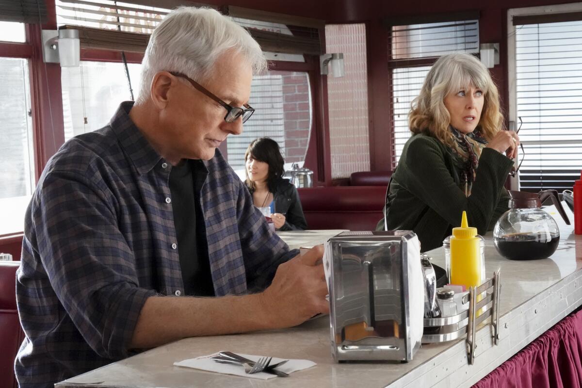 Mark Harmon and Pam Dawber sitting at a diner counter in "NCIS" on CBS.