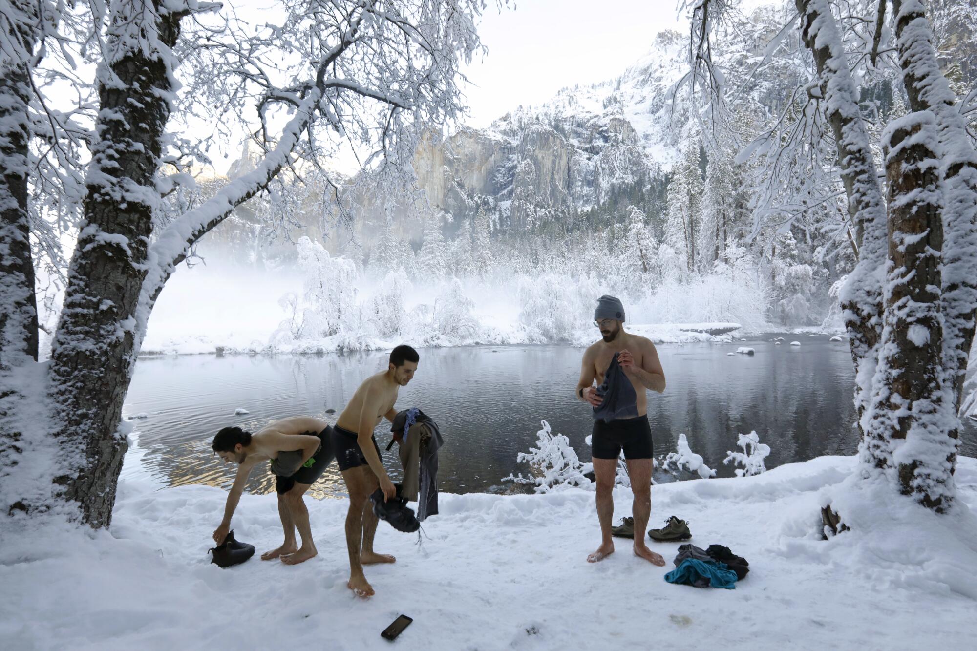 Three people in swimsuits in the snow.