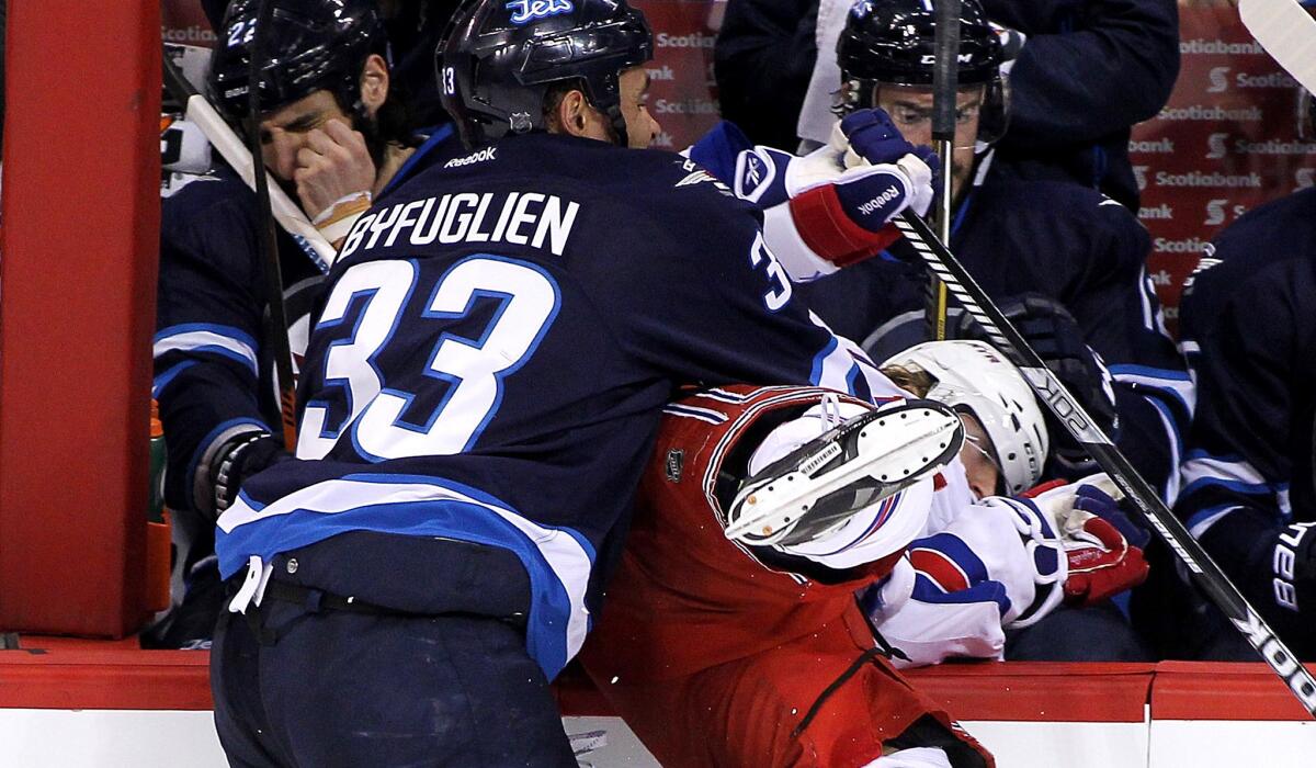 Defenseman Dustin Byfuglien, checking Rangers left wing Carl Hagelin into the boards during a March 31 game in Winnipeg, has helped the Jets win recently with dominating defense.