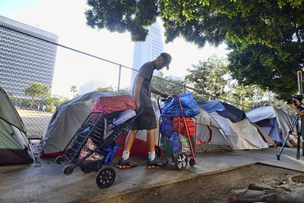 A homeless man moves his belongings from a street near Los Angeles City Hall.