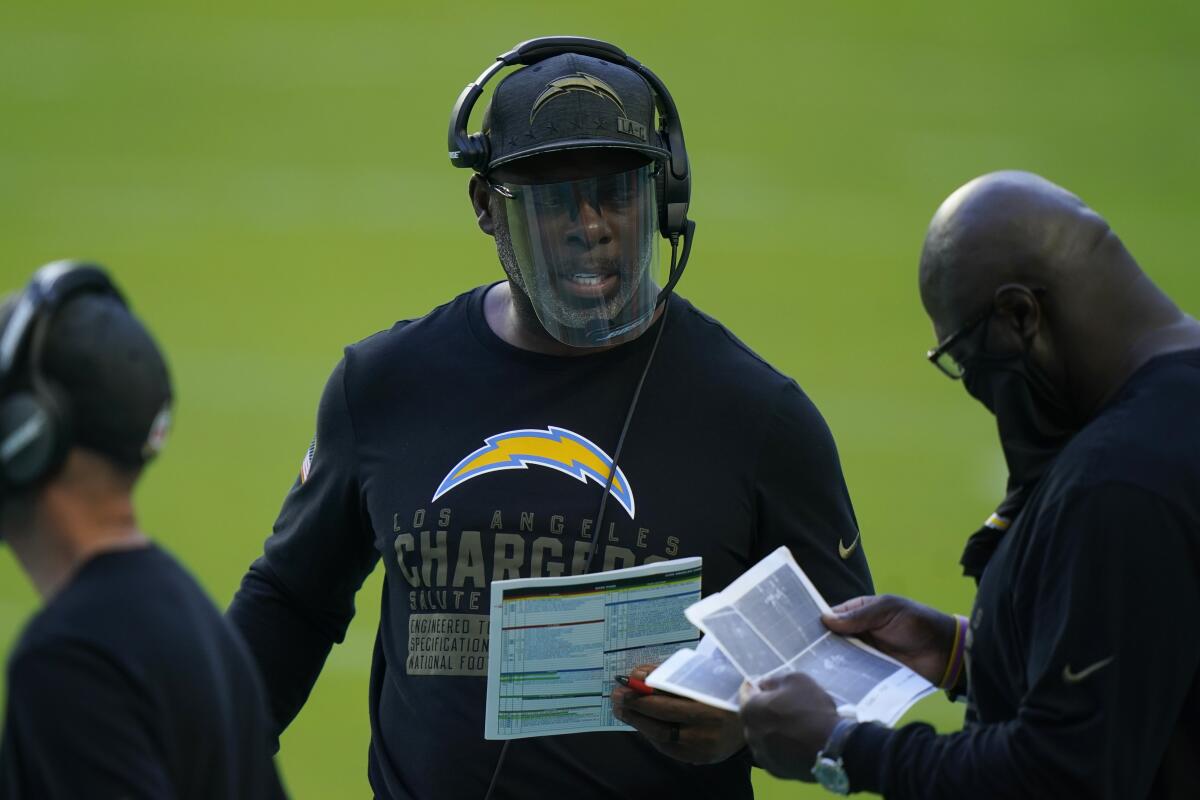 Chargers head coach Anthony Lynn, center, talks to his staff on the sidelines.