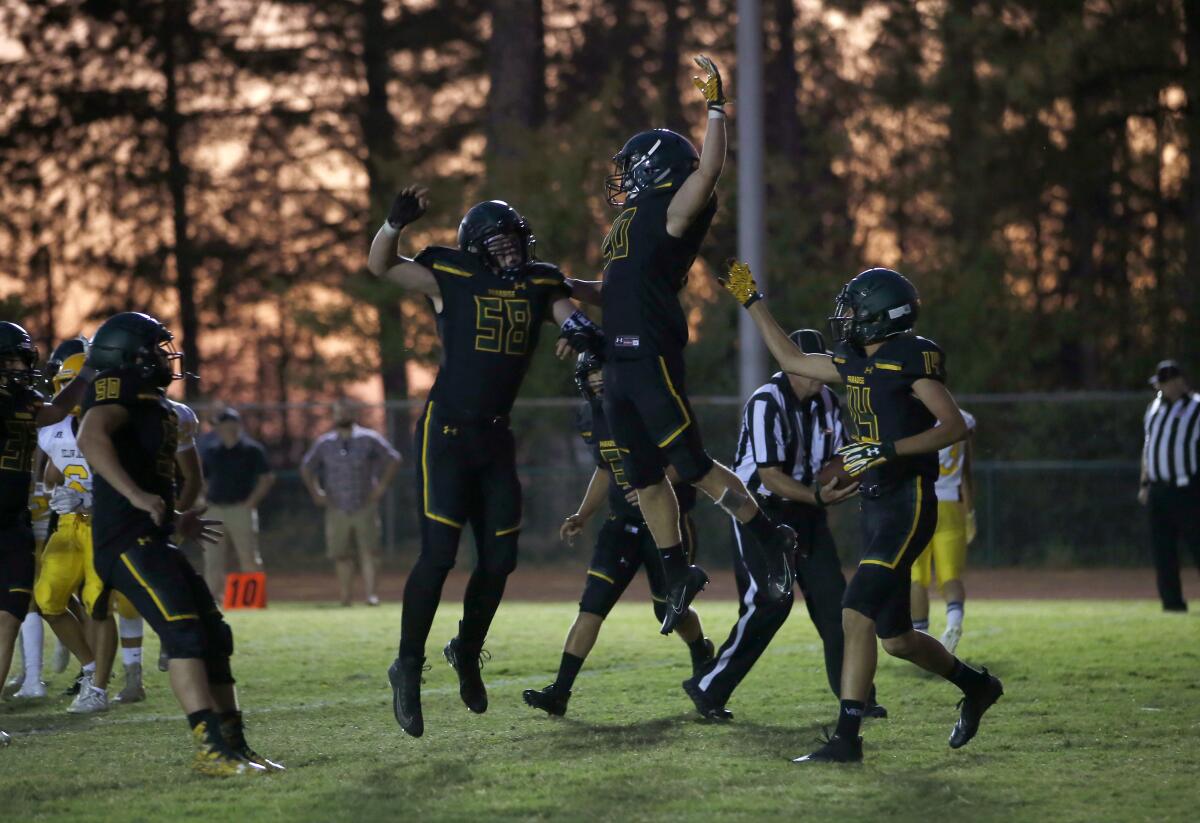 Paradise running back Lucas Hartley, center right, celebrates with teammate Kasten Ortiz after scoring the first touchdown of the year for the team in their high school football game against Williams, in Paradise, Calif., Friday Aug. 23, 2019. This is the first game for the school since a wildfire in November killed multiple people and destroyed nearly 19,000 buildings, including the homes of most of the Paradise players. (AP Photo/Rich Pedroncelli)
