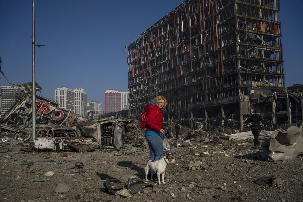 Irina Zubchenko walks with her dog Max amid the destruction caused by the shelling of a shopping center