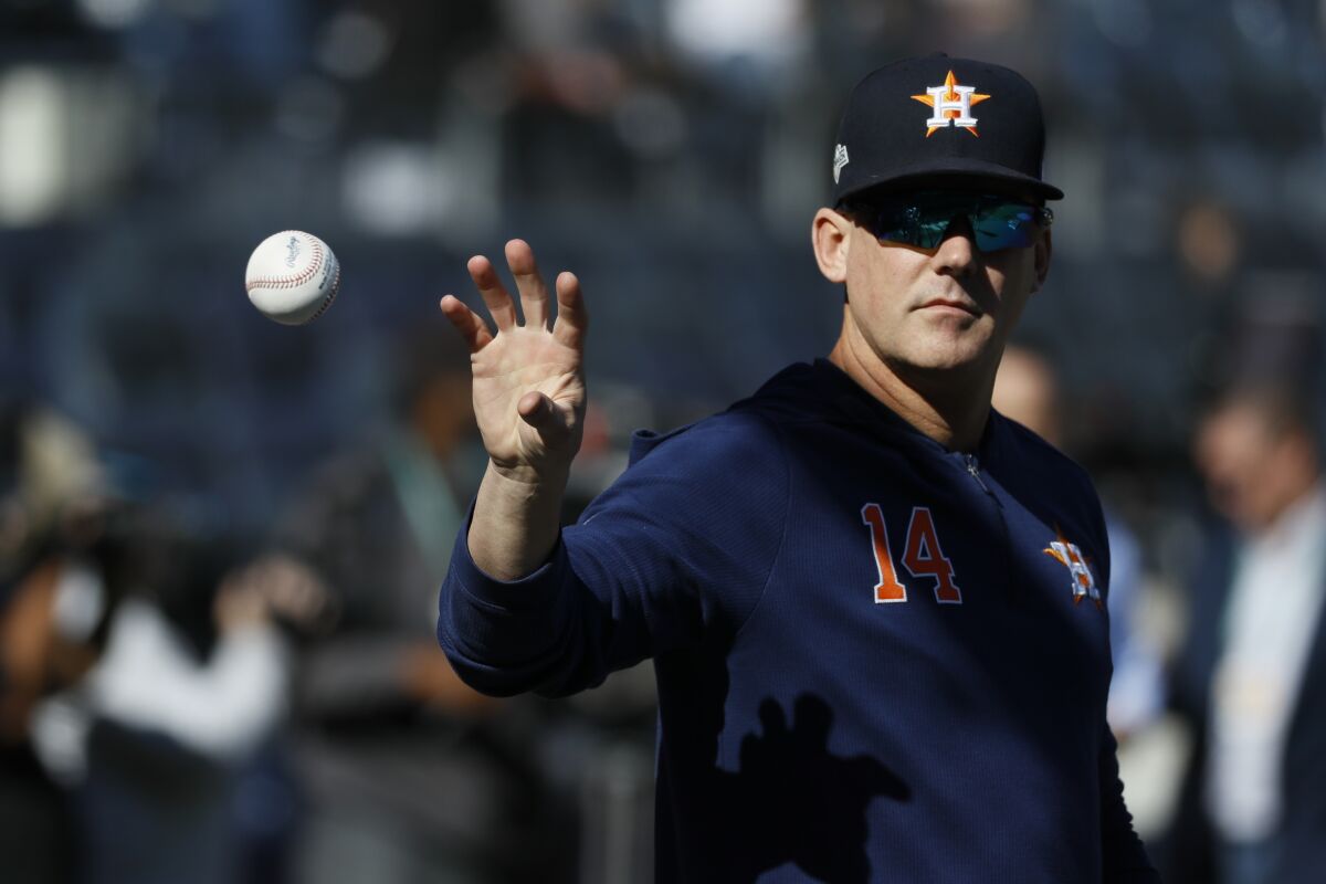 Houston Astros manager AJ Hinch catches a ball before a playoff game in 2019.