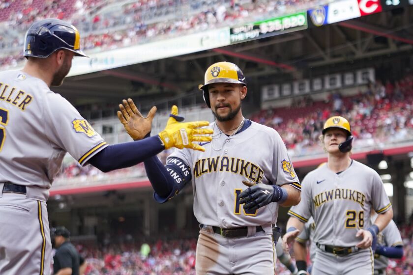 Milwaukee Brewers' Blake Perkins, center, celebrates with Owen Miller, left, after hitting a grand slam against the Cincinnati Reds in the third inning of a baseball game in Cincinnati, Saturday, June 3, 2023. (AP Photo/Jeff Dean)